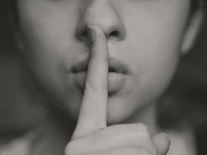 woman holding her finger up to her mouth telling a secret to delegate