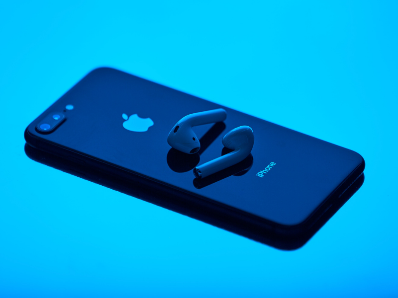 apple iphone with earbuds on a bright blue background