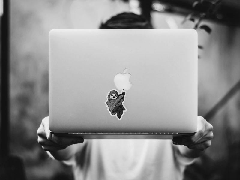 a man holding an apple laptop with outstretched arms