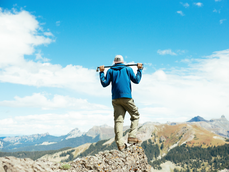 young man on top of a mountain with blue sky