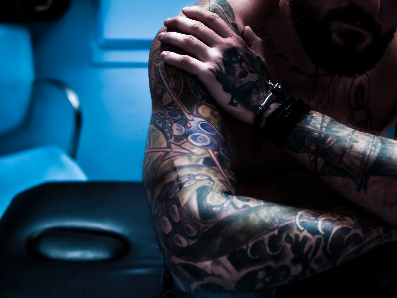 close up shot of a tattooed man sitting in his shop