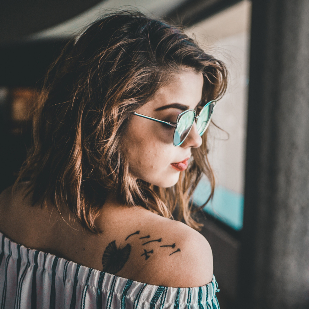 young woman with sunglasses and a dandelion tattoo