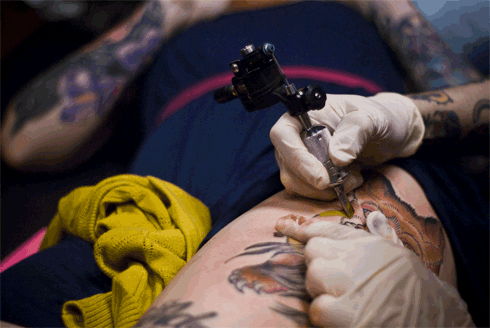 tattoo artist tattooing a leg