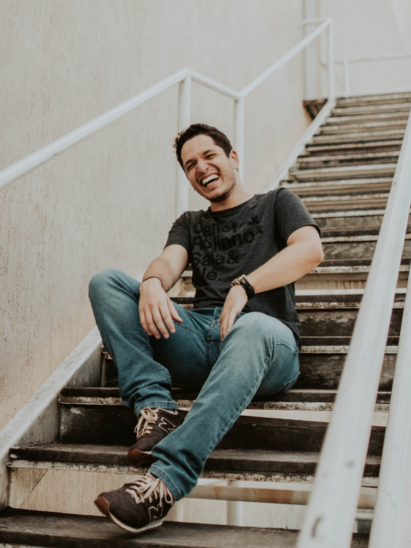 a laughing man on the stairs wearing a t-shirt and jeans