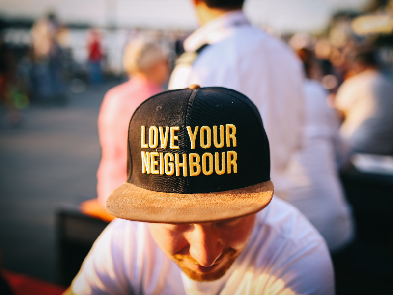 close up of a man wearing love your neighbor hat