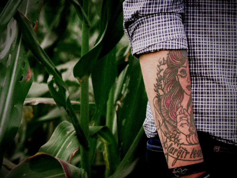 tattooed arm close up in front of greenery
