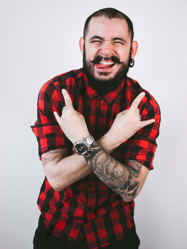 man with a handlebar mustache giving the devil horns and laughing