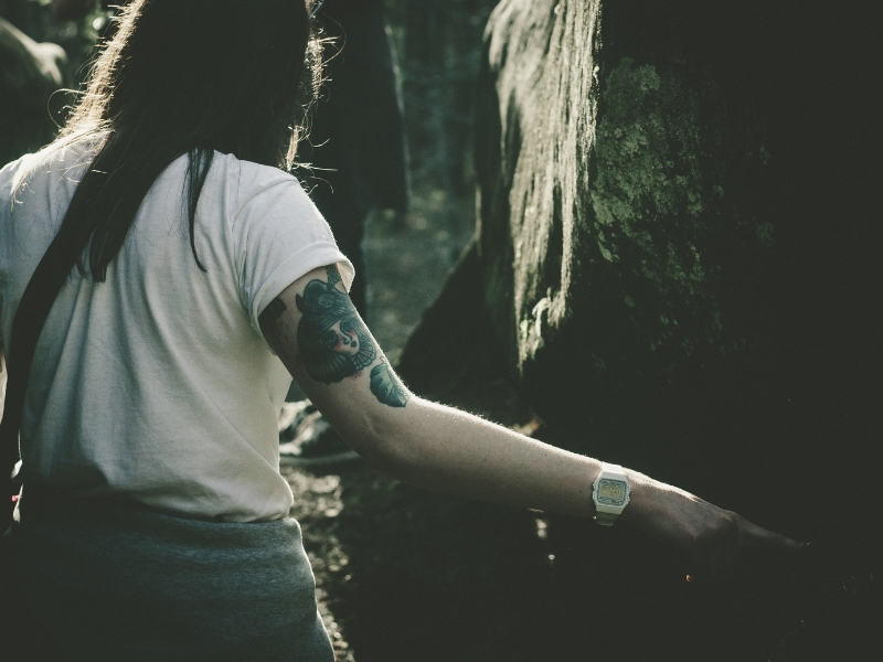 a woman with cap sleeve tattoo stands in the woods