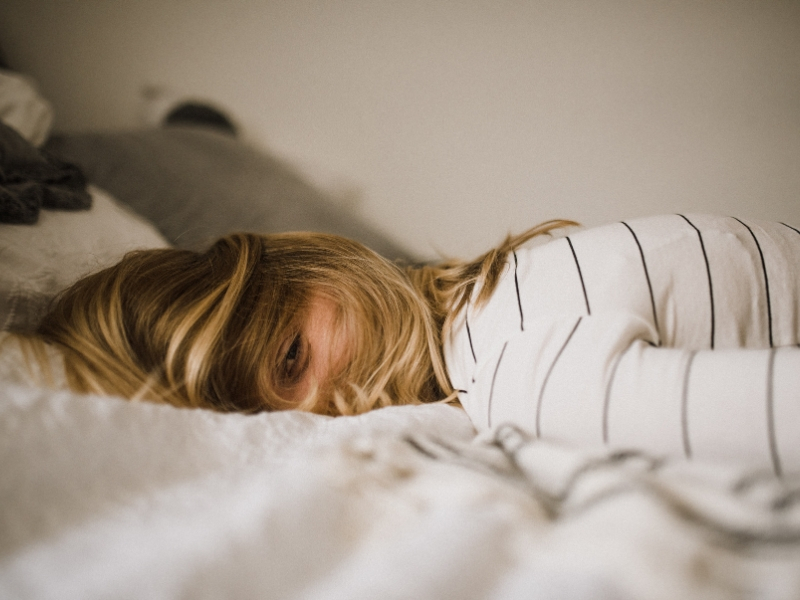 woman lies on a bed exhausted from burnout