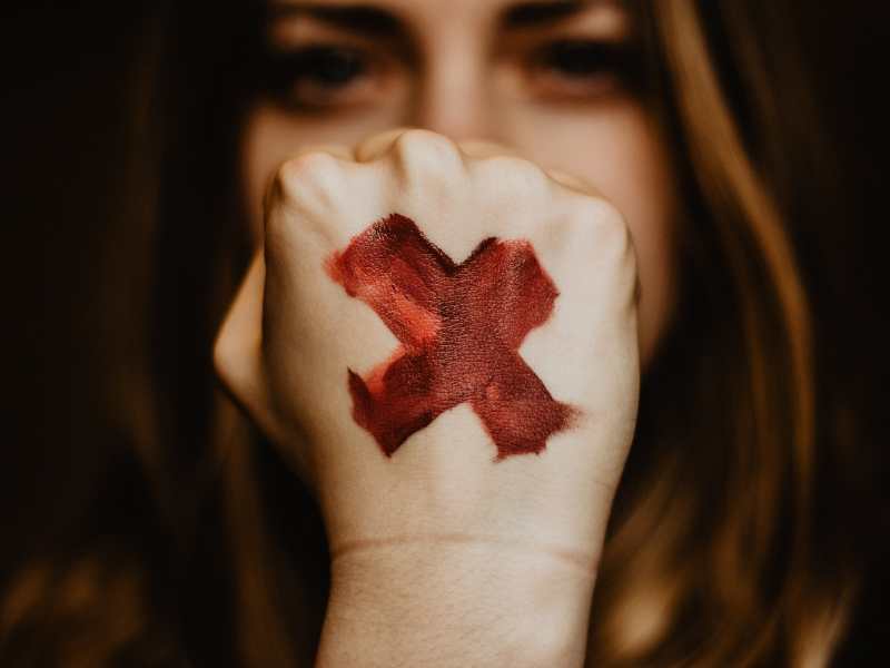 close up of a woman's fist with a red "x" on it