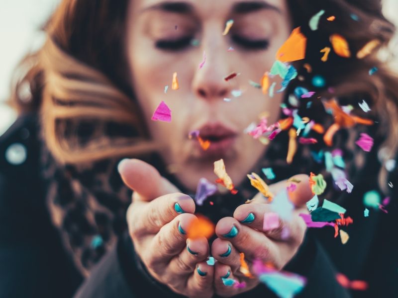 a woman is blowing confetti which is a great client visit decoration ideas