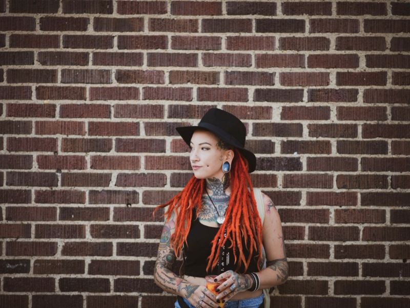 young woman in front of a wall with tattoos and dreads