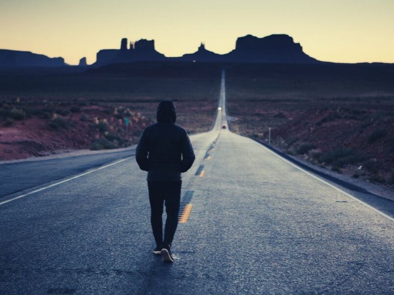 man walks down the middle of an empty highway