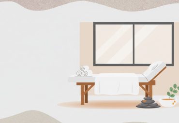 Quiet day spa treatment room with a treatment table, rolled towels, and warm stones