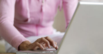 woman wearing pink hoodie on laptop